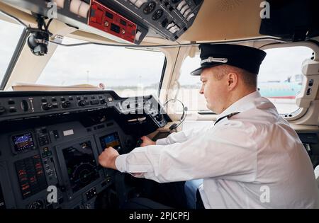 Pilota in abbigliamento formale siede nel pozzetto e controlla l'aereo Foto Stock