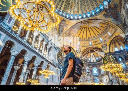 Uomo turistico godendo Hagia Sofia, Ayasofya interni a Istanbul, Turchia, architettura bizantina, punto di riferimento della città e meraviglia architettonica del mondo. Turkiye Foto Stock