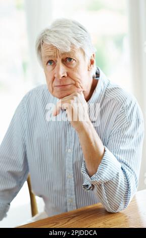 Ricordando i buoni vecchi giorni. un uomo anziano seduto pensierosamente al coperto. Foto Stock