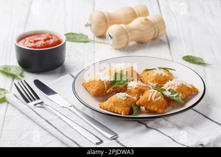 Ravioli italiani fritti in panatura con salsa di pomodoro caldo marinara, primo piano sul tavolo di legno. Orizzontale Foto Stock