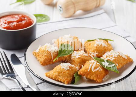 Ravioli fritti fatti in casa con salsa Marinara e parmigiano sul tavolo di legno. Orizzontale Foto Stock