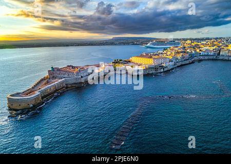 Veduta aerea del castello di Maniace, dell'isola di Ortigia e della città di Siracusa immersa nella calda luce del tramonto. Siracusa, Sicilia, Italia Foto Stock