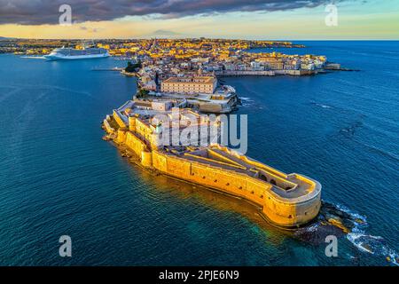 Veduta aerea del castello di Maniace, dell'isola di Ortigia e della città di Siracusa immersa nella calda luce del tramonto. Siracusa, Sicilia, Italia Foto Stock