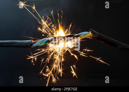 fumo da fiamma e scintille su un cavo elettrico, concetto di rischio di incendio, primo piano soft focus Foto Stock