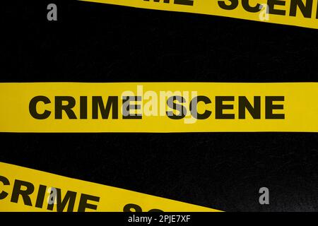 Scena del crimine nastro barricata giallo avvertimento e segnale di attenzione su sfondo nero scuro. Foto Stock