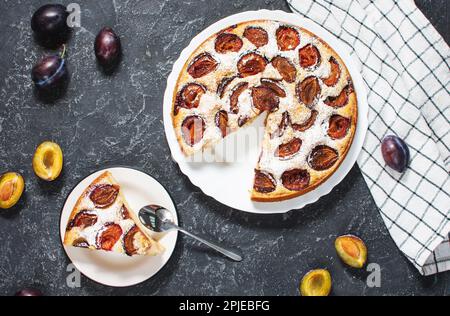 Deliziosa crostata di prugne fatta in casa con zucchero in polvere sul tavolo in pietra nera. Vista dall'alto Foto Stock