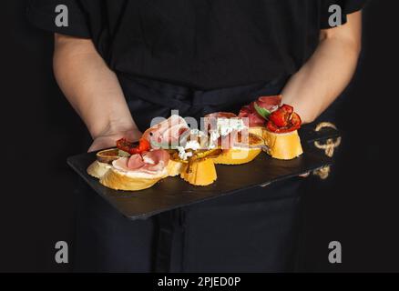 Tavola di antipasti con un tradizionale set spagnolo di tapas nelle mani dello chef Foto Stock