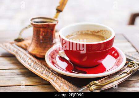 Il tradizionale caffè turco viene servito in una tazza e una caffettiera metallica sulla terrazza di un caffè di strada. Foto Stock