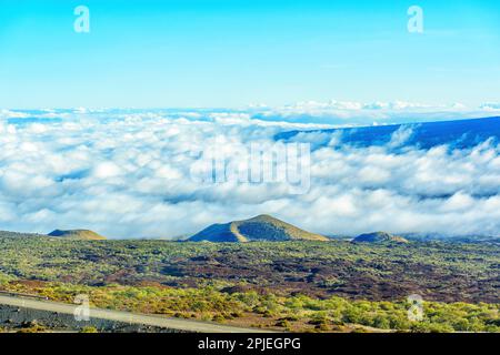 Il paesaggio di Mauna Kea visto dall'alto, con uno strato di nuvole che sovrastano la valle. Foto Stock