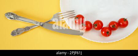 Banner pomodori ciliegini su un piatto con posate. Concetto di alimento di dieta. Foto Stock