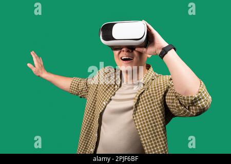 Un uomo asiatico di mezza età eccitato che usa gli occhiali VR, tocca qualcosa di invisibile, sperimenta l'avventura in realtà virtuale Foto Stock