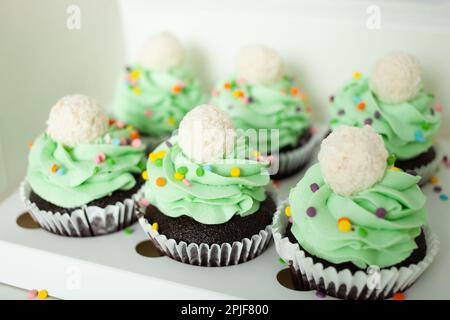 Il pasticciere professionale preparò tortini sotto forma di alberi di Natale. Dolci deliziosi per ogni vacanza, regalo. Panna montata verde. Foto Stock