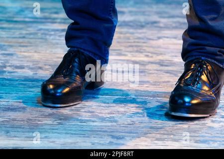 Pantaloni da uomo in movimento da palco con righe e scarpe in pelle per ballare irlandese sul pavimento. Stivali da lavoro neri per ballare al tap con riflessi Foto Stock