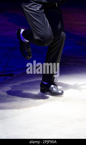 Pantaloni da uomo in movimento da palco con righe e scarpe in pelle per ballare irlandese sul pavimento. Stivali da lavoro neri per ballare al tap con riflessi Foto Stock