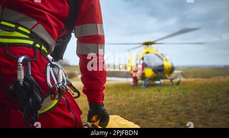 Focalizzazione selettiva sull'imbracatura di sicurezza paramedica del servizio di emergenza davanti all'elicottero. Temi di salvataggio, aiuto e speranza. Foto Stock