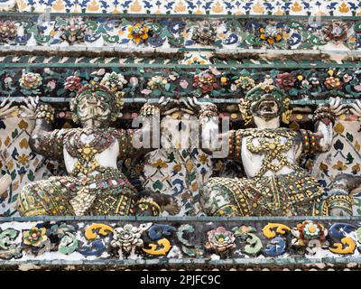 Queste magnifiche statue ornate adornano la facciata di Wat Arun, catturando l'occhio con i loro colori vivaci e disegni intricati. Come guardiani del te Foto Stock