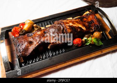 Gamba di agnello arrosto su tavolo di legno. Piatti della cucina caucasica Foto Stock