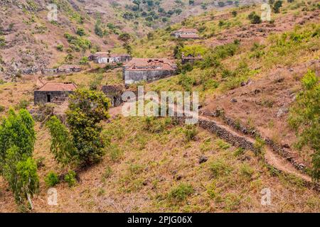 Case di pietra e un sentiero su una montagna con cespugli e erba nel nord montuoso dell'isola di Santiago, Cabo Verde Foto Stock