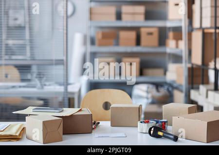 Parte del posto di lavoro del responsabile imballaggio merci e vestiti ordinati dai clienti in linea nella stanza spaziosa di deposito con molti ripiani Foto Stock