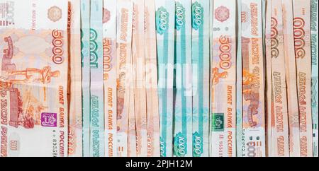 Sfondo orizzontale di carta moneta sparsa in tagli di mille e cinquemila rubli russi Foto Stock