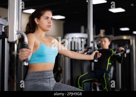 Ragazza giovane che esegue esercizi di petto in macchina farfalla Foto Stock