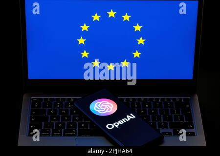 Logo OpenAI visto su smartphone e bandiera dell'UE sul laptop. Concetto per la regolamentazione degli strumenti di intelligenza artificiale in Europa. Stafford, Regno Unito, 3 aprile 2023 Foto Stock