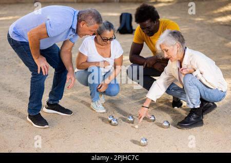 Compagnia di persone mature e amichevoli che giocano a bocce nel parco Foto Stock