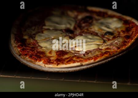 Formaggio appena cotto e pizza al pomodoro. Cucina casalinga. Sfondo scuro. Foto Stock