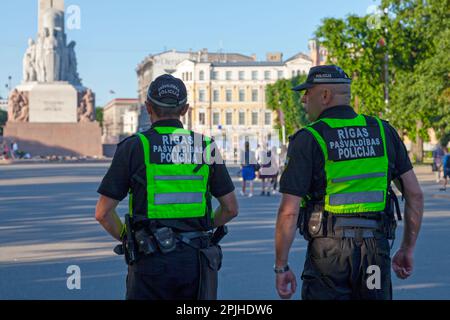 Riga, Lettonia - Giugno 14 2019: Due ufficiali della polizia municipale di riga (Rīgas pašvaldības policija) pattugliano la piazza vicino al Monumento alla libertà. Foto Stock