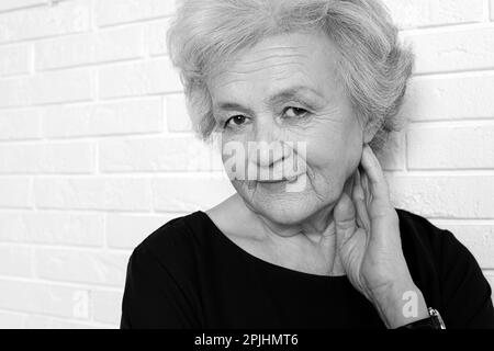 Ritratto di donna matura vicino al muro di mattoni. Fotografia in bianco e nero Foto Stock