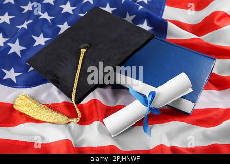 Cappello nero, diploma e libro sulla bandiera americana Foto Stock