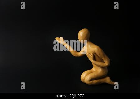 Plastilina figura di uomo che chiede aiuto su sfondo nero. Spazio per il testo Foto Stock