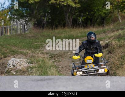 Guida avventurosa di moto ATV. Un uomo guida un quad su strade pericolose Foto Stock