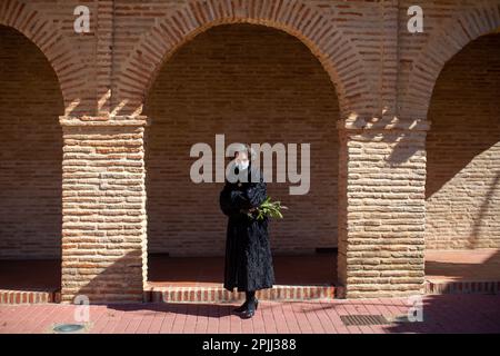 Una donna tiene un ramo di alloro, in uno degli archi della chiesa di San Lorenzo in Sahagún. La processione delle Palme rappresenta il passaggio di Gesù al suo trionfante ingresso a Gerusalemme. La processione ha girato le strade della città accompagnata da fedeli con bouquet e la band sinfonica della città. Credit: SOPA Images Limited/Alamy Live News Foto Stock