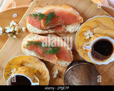 Sandwich con salmone e caffè su un bagel di legno e caffè Foto Stock