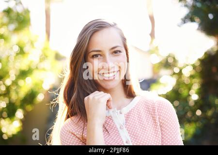 La sua bellezza splende come il sole. una bella giovane donna in piedi alla luce del sole. Foto Stock