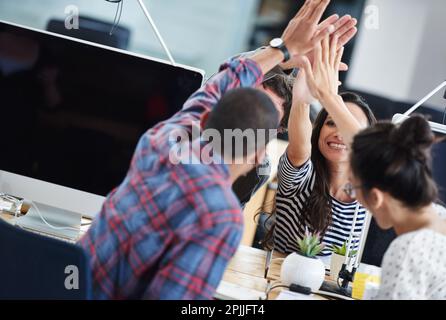 Fate della creatività un lavoro. un gruppo di giovani impiegati seduti ai loro computer e che si accaniscono l'un l'altro. Foto Stock