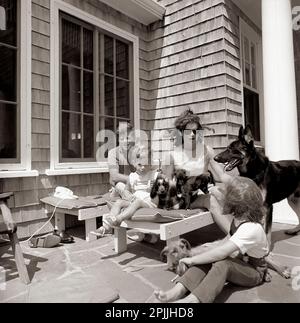 ST-C267-6-63 14 agosto 1963 il presidente John F. Kennedy, la First Lady Jacqueline Kennedy e i loro figli, Caroline Kennedy e John F. Kennedy Jr., siedono con i loro cani, Shannon, Wolf, White Tips, Blackie, E Clipper, a casa Brambletyde su Squaw Island, Hyannis Port, Massachusetts. Si prega di accreditare 'Cecil Stoughton. Fotografie della Casa Bianca. John F. Kennedy Presidential Library and Museum, Boston' Foto Stock