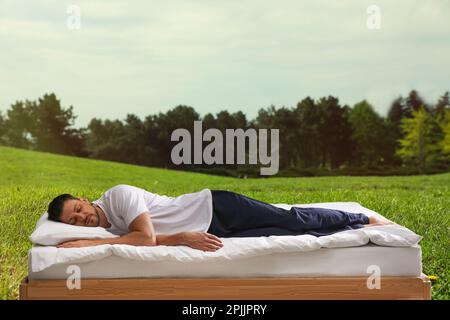 Uomo che dorme a letto e bella vista del prato verde sullo sfondo. Dormi bene - resta in salute Foto Stock