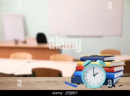 Turchese sveglia e cancelleria diversa su tavolo di legno in classe, spazio per il testo Foto Stock