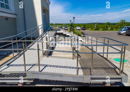 Una rampa per sedie a rotelle o parapetto per passeggino è un piano inclinato installato in aggiunta alle scale, messa a fuoco selettiva Foto Stock