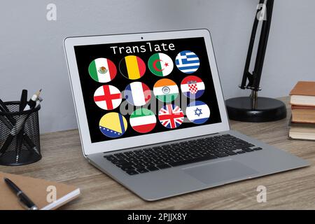 Ambiente di lavoro con notebook e immagini di diverse bandiere sullo schermo vicino a una parete grigio chiaro all'interno Foto Stock