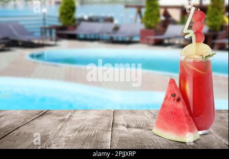 Gustosa bevanda di cocomero e frutta fresca su un tavolo di legno vicino alla piscina all'aperto, spazio per testo Foto Stock