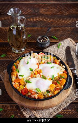 Shakshouka in padella. Uova fritte con verdure, pomodoro, pepe, zucca e cipolla Foto Stock