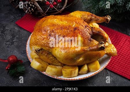 Pollo arrosto e patate con decorazione natalizia. Cibo tradizionale per Natale o il giorno del Ringraziamento Foto Stock