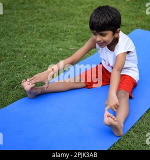 Asian Smart Kid fare yoga posa nel parco sociale all'aperto, la posa yoga dei bambini. Il bambino che fa l'esercitazione di Yoga Foto Stock