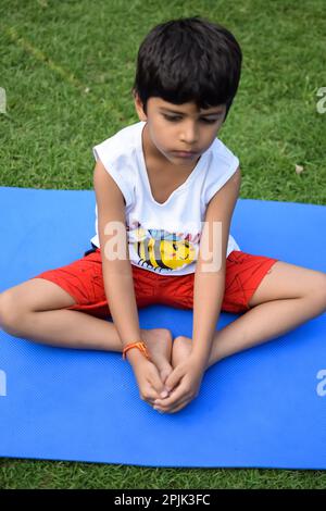 Asian Smart Kid fare yoga posa nel parco sociale all'aperto, la posa yoga dei bambini. Il bambino che fa l'esercitazione di Yoga Foto Stock