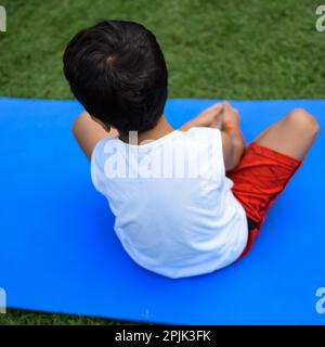 Asian Smart Kid fare yoga posa nel parco sociale all'aperto, la posa yoga dei bambini. Il bambino che fa l'esercitazione di Yoga Foto Stock