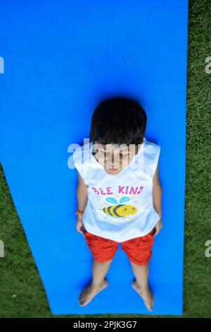 Asian Smart Kid fare yoga posa nel parco sociale all'aperto, la posa yoga dei bambini. Il bambino che fa l'esercitazione di Yoga Foto Stock