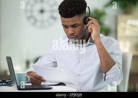 uomo d'affari africano concentrato in cuffie Foto Stock